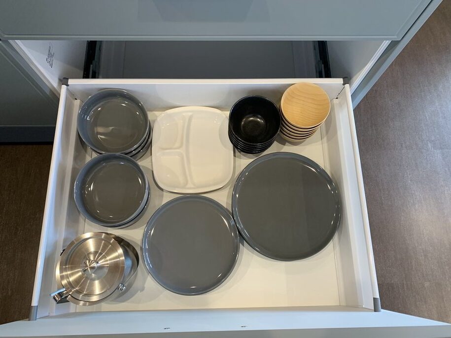 引き出しに整然と並んだ食器類と鍋
